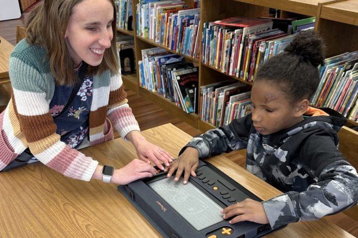 Teacher supporting a child using Monarch tactile display to explore tactile graphics in a learning environment