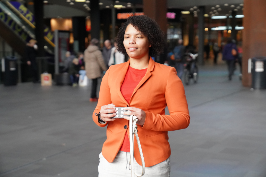 A user using the Hable One in a public setting. Une personne utilisant le clavier braille Hable One dans un environnement extérieur.