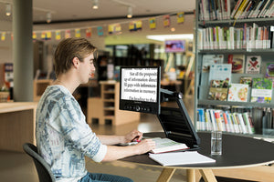 Picture of a user in a library using the ClearView Go 15 inch to read a book
