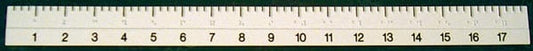 A close-up of a white plastic ruler with black printed numbers and measurement markings, spanning horizontally across the frame with Braille 