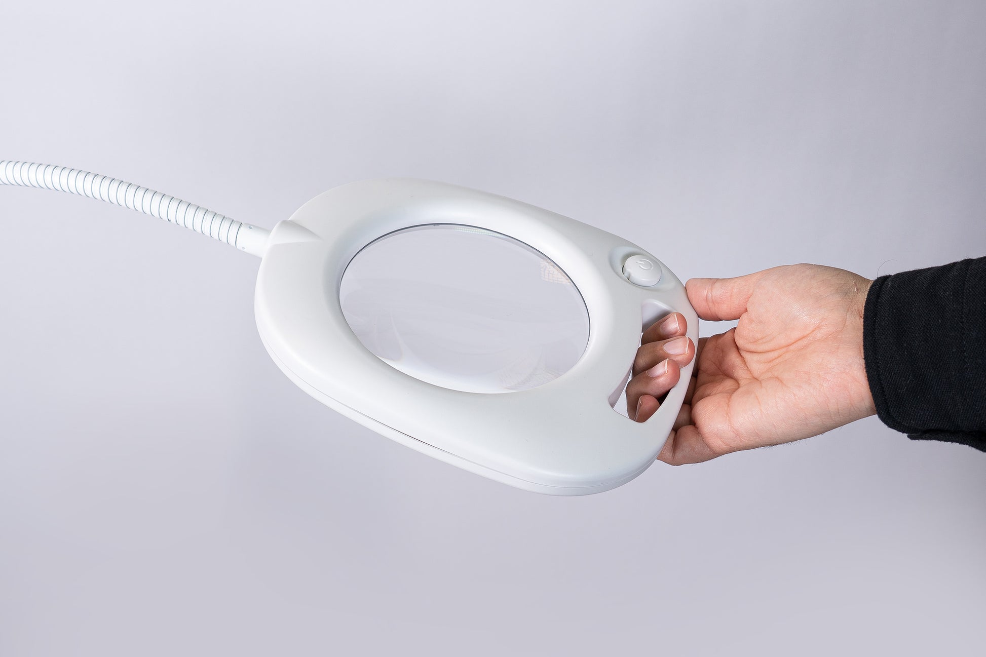 Hand holding the handle of the lamp with magnifier.