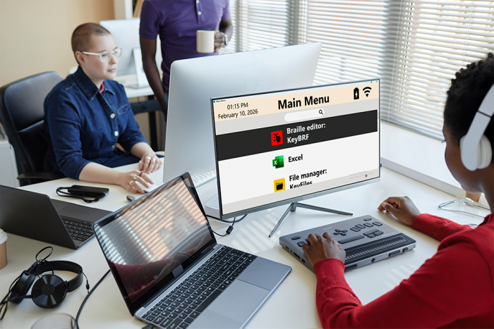 User operating BrailleNote Evolve 32 connected to a computer displaying accessible menu and applications
