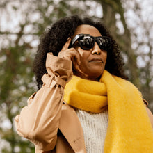 Charger l&#39;image dans la visionneuse de la galerie,An image of a woman of colour wearing the Envision Glasses with the Smith Optics Frame. She wears a light fall jacket and bright yellow scarf.