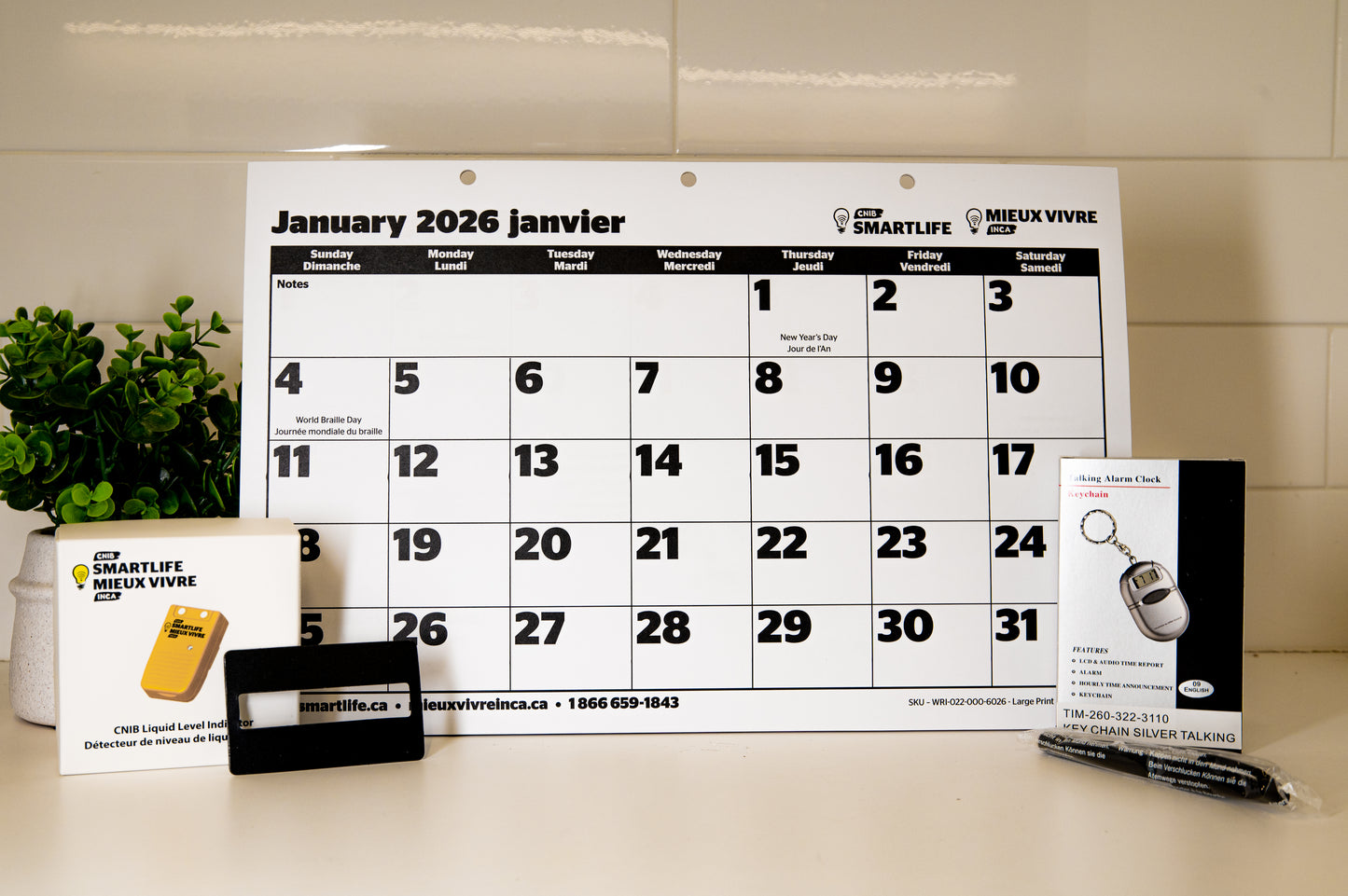 Calendar for January 2026 with Smartlife branding on a table. CNIB liquid level indicator, plastic signature guide, talking keychain and pentel pen