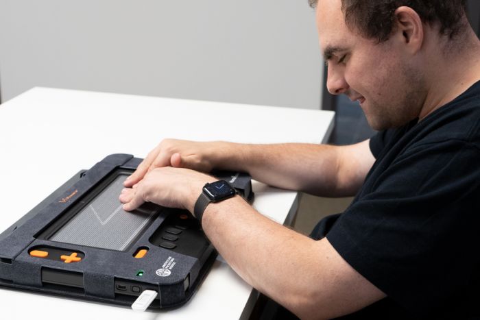 User reading tactile graphics on the Monarch multi-line braille display using both hands