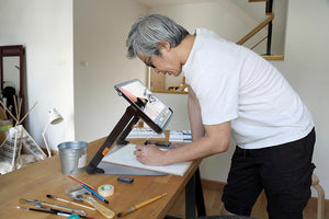 Gentleman using the Explore 12 with Stand to magnify a drawing